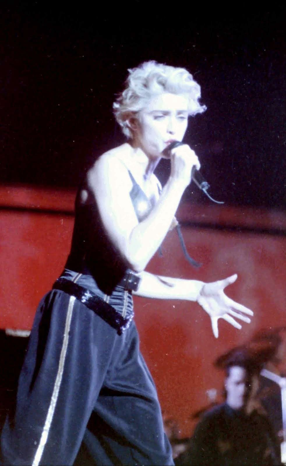 Madonna performs at Wembley in 1987 in a fitted sleeveless bodice, collared shirt and wide-leg trousers.