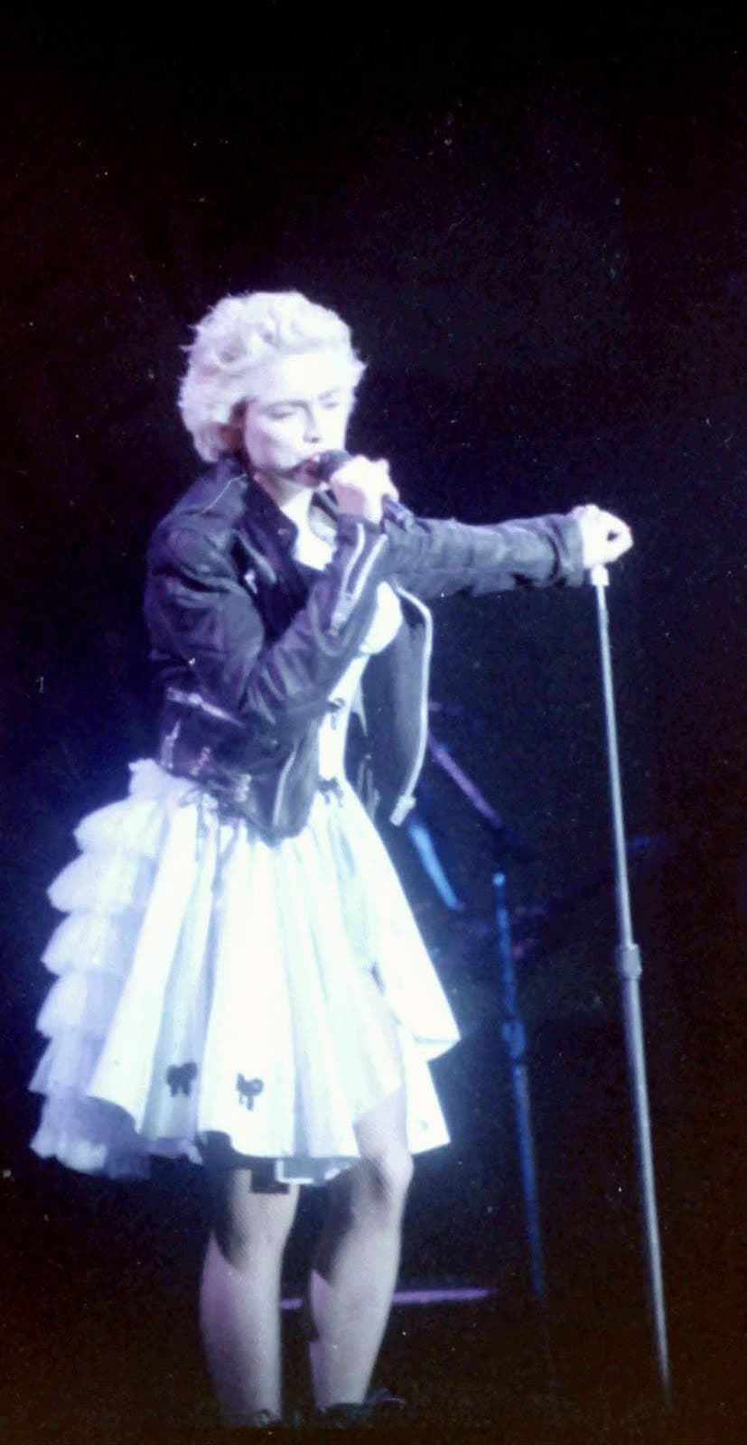 Madonna performs at Wembley in 1987 wearing a cropped black biker jacket over a full tiered skirt.